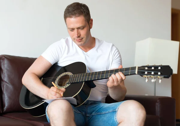 Handsome man compose a song on the guitar. — Stock Photo, Image