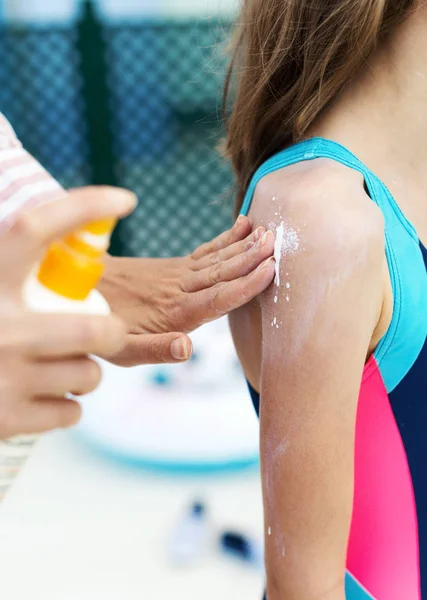 La mano di donna che applica la crema abbronzante a bambino indietro . — Foto Stock