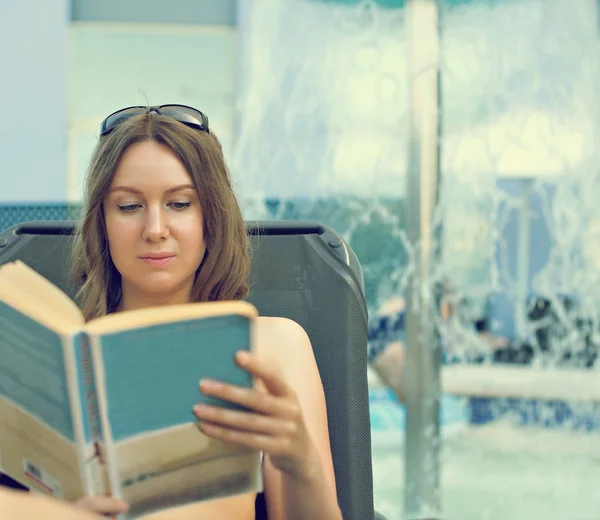 Kobieta czytająca książkę przy basenie wody. — Zdjęcie stockowe