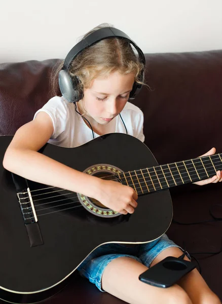 Little girl with headphones playing the guitar. — Stock Photo, Image