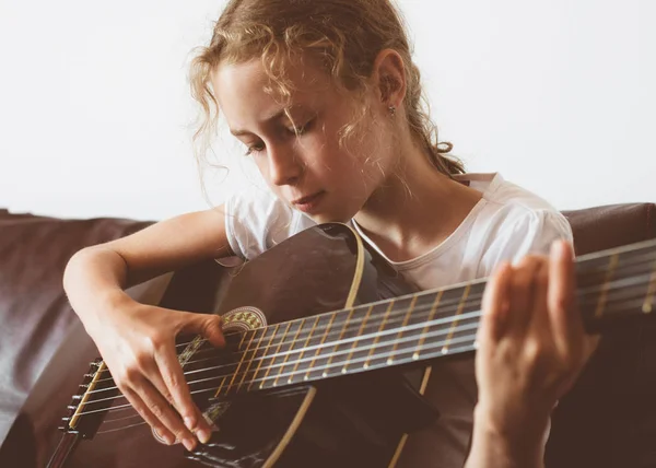 Lilla flickan lär sig att spela gitarr. — Stockfoto