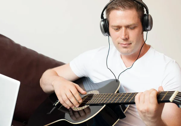 Knappe man met hoofdtelefoon gitaar spelen. — Stockfoto