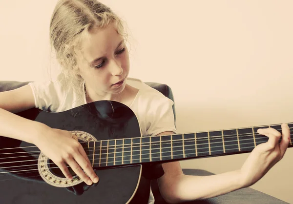 Mała dziewczynka uczy się grać na gitarze. — Zdjęcie stockowe