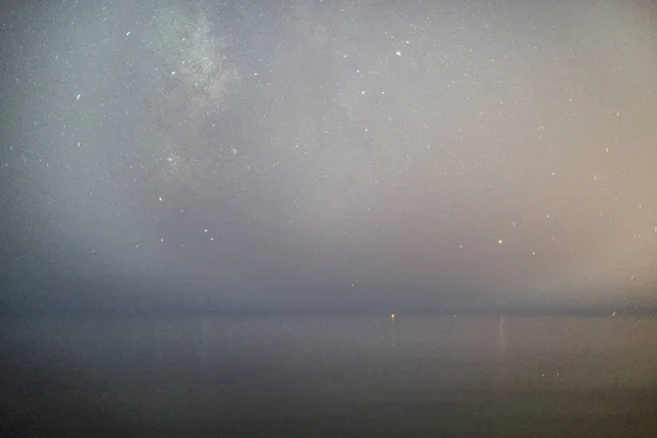 Gece gökyüzünde yıldızlar ve bulutsu ile okyanus yukarıda. — Stok fotoğraf