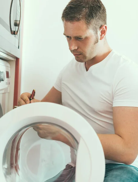 Técnico masculino reparando máquina de lavar roupa, escrevendo o código do fabricante . — Fotografia de Stock