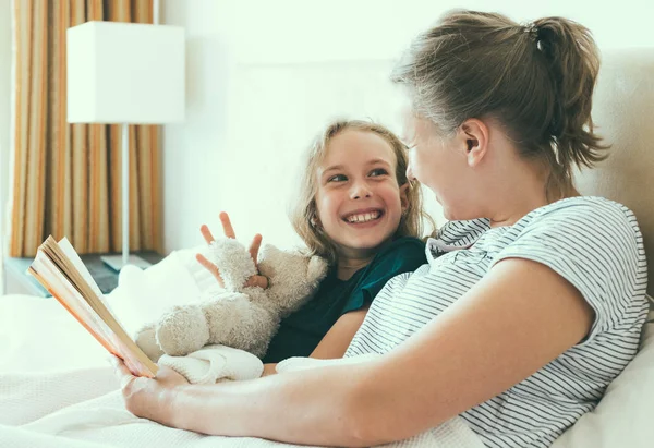 Mère et fille lisant un livre au lit . — Photo