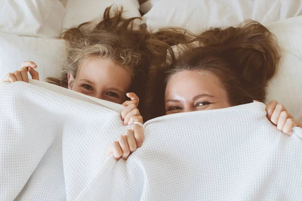 Mother and daughter hiding under blanket. — Stock Photo, Image