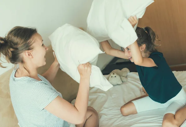 Mother and daughter fighting by pillows. — Stock Photo, Image