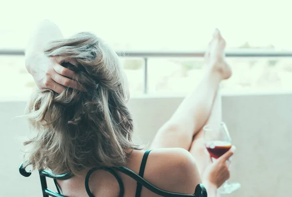 Mulher desfrutando de seu vinho tinto na varanda . — Fotografia de Stock