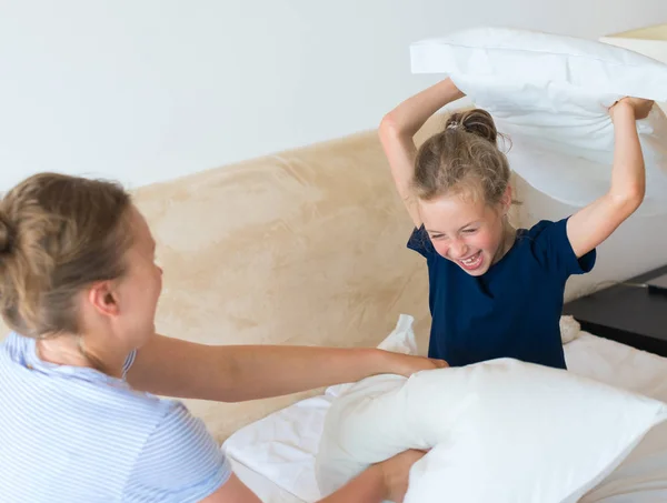 Moeder en dochter vechten door kussens. — Stockfoto