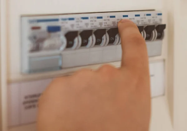 Male hand switching on fuse board. — Stock Photo, Image