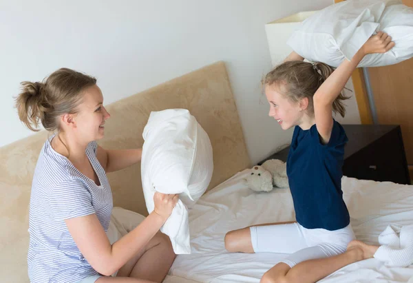 Moeder en dochter vechten door kussens. — Stockfoto