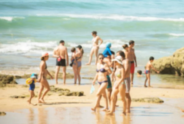 Un sacco di persone che riposano sulla spiaggia estiva. Immagine sfocata . — Foto Stock