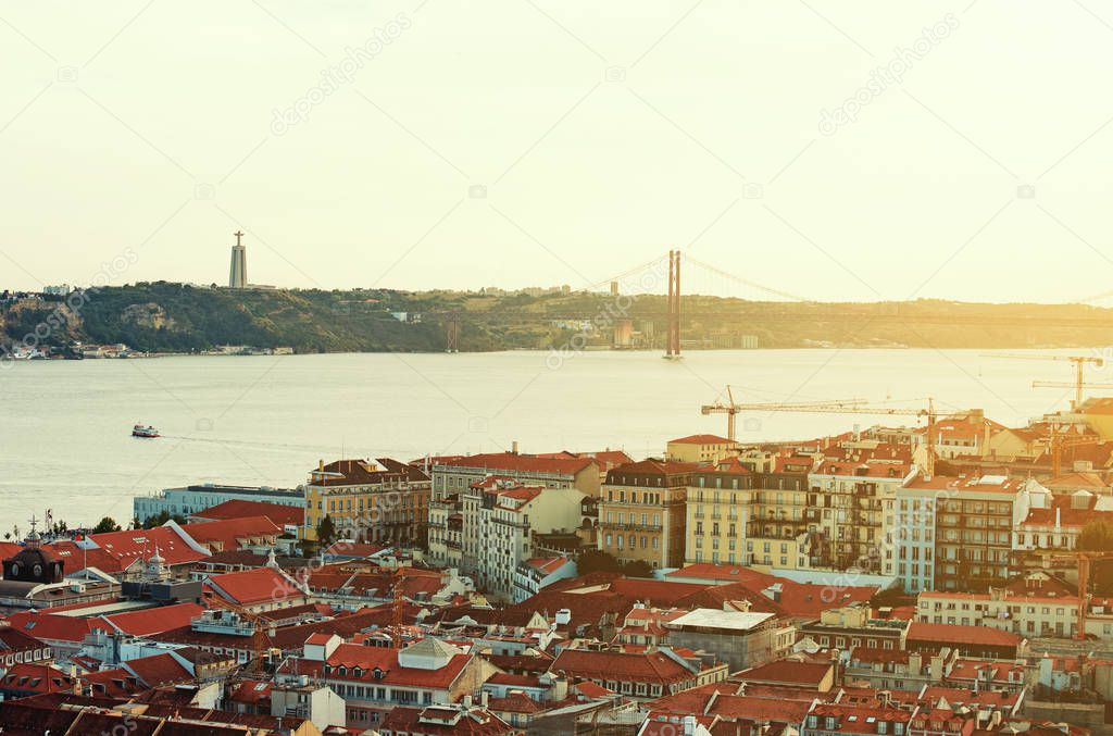 Alfama downtown and the 25 April Bridge in Lisbon at sunset.