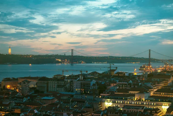 Centro de Alfama e a Ponte 25 de Abril em Lisboa à noite . — Fotografia de Stock