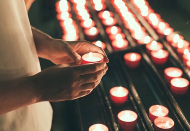 Woman holding candle near altar in church. clipart
