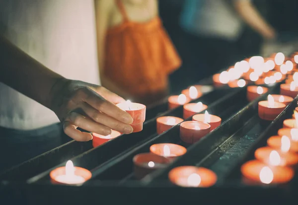 Woman puts a candle on altar in church. — Stock Photo, Image