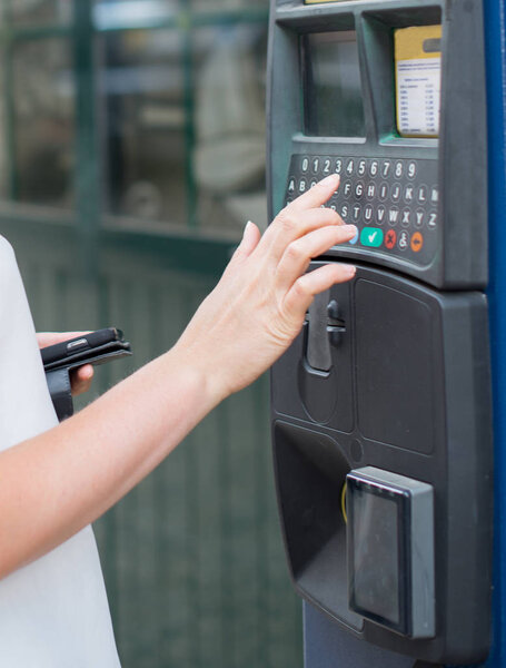 Woman using parking machine on the street.