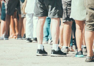 İnsanlar sokakta bir sırada ayakta.