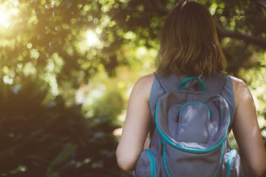 Ormanın içinde sırt çantası olan kadın. Arkadan görüntülemek.