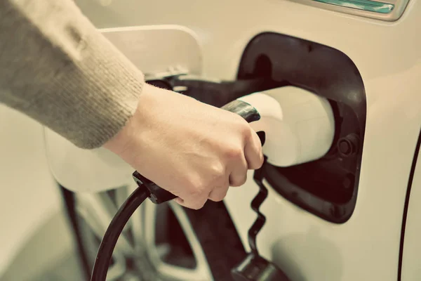 Mão segurando ficha elétrica para carregar carro elétrico . — Fotografia de Stock