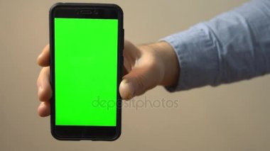 Yeşil ekranlı el ele tutuşan cep telefonu. Krom anahtar.