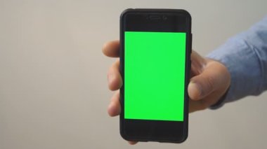 Yeşil ekranlı el ele tutuşan cep telefonu. Krom anahtar.