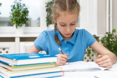 küçük kız ödevini evde yapıyor.
