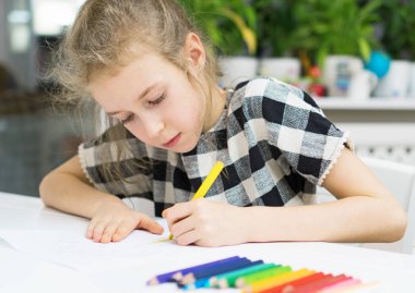 Little girl drawing with pencil at home. clipart