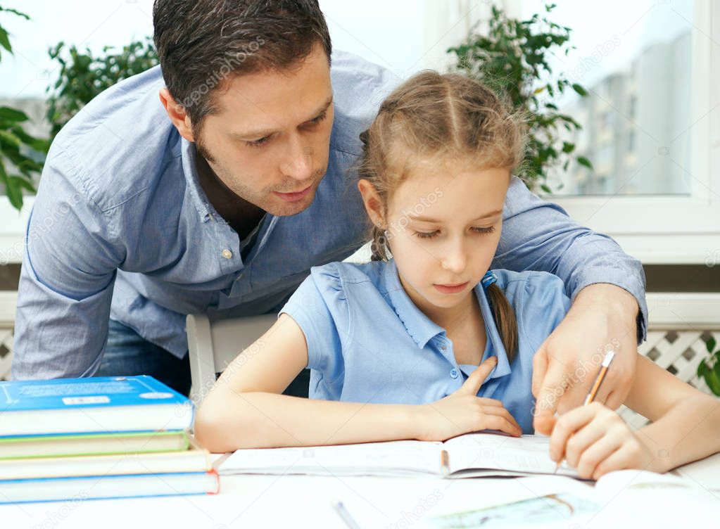 Father helping daughter with homework at home.