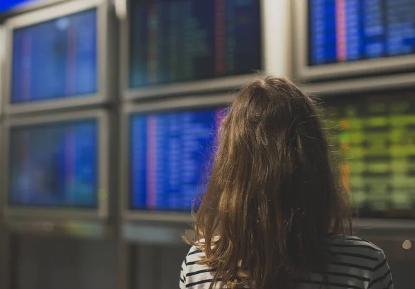 Kleines Mädchen vor Flugplan am Flughafen. — Stockfoto