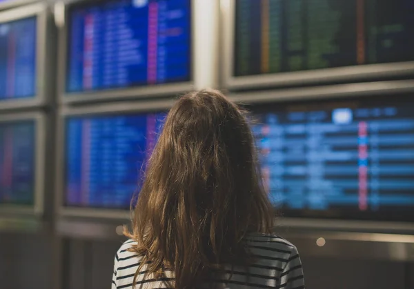 Kleines Mädchen vor Flugplan am Flughafen. — Stockfoto