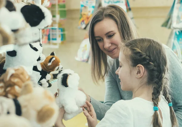 Femme et sa fille choisissant jouet dans le magasin d'enfants . — Photo