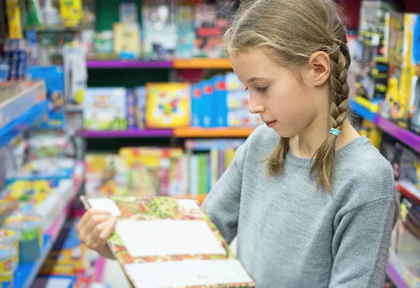 Девочка выбирает игрушки в детском магазине . — стоковое фото
