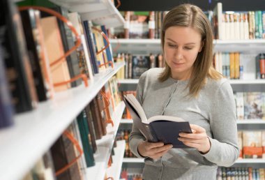 Kadın bir kitapçı kitap okuyor.