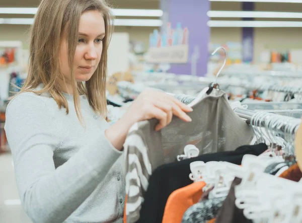 Woman choosing sweater in clothing store. — Stock Photo, Image