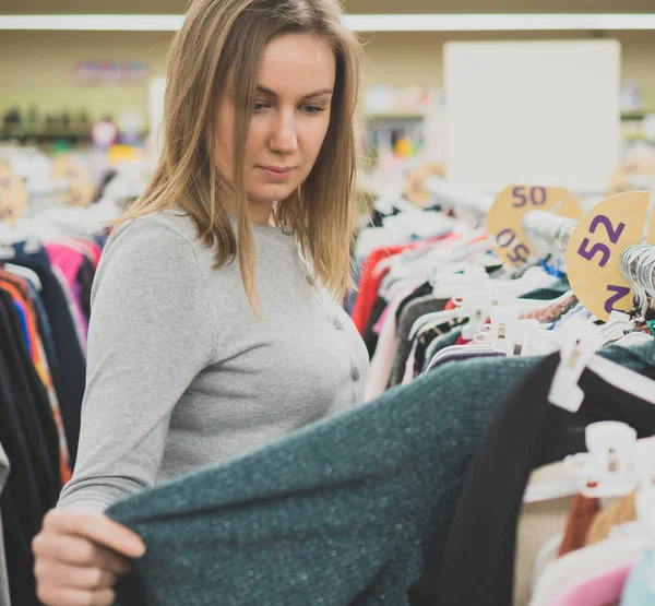 Женщина выбирает свитер в магазине одежды . — стоковое фото