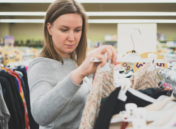 Vrouw kiezen trui in kleding opslaan. — Stockfoto