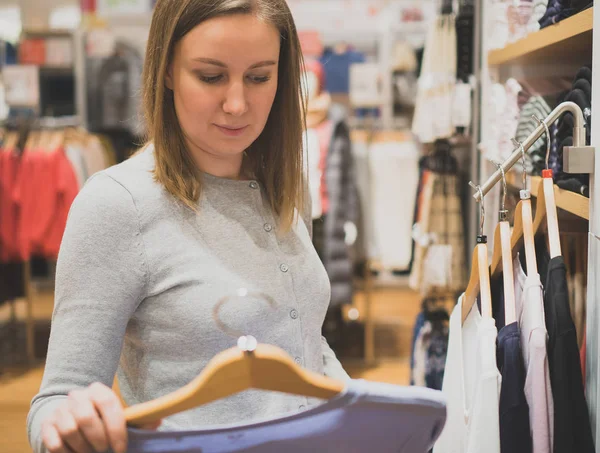 Жінка вибирає светр в магазині одягу . — стокове фото