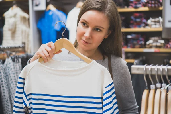 Przechowywać kobieta wybierając sweter w odzież. — Zdjęcie stockowe