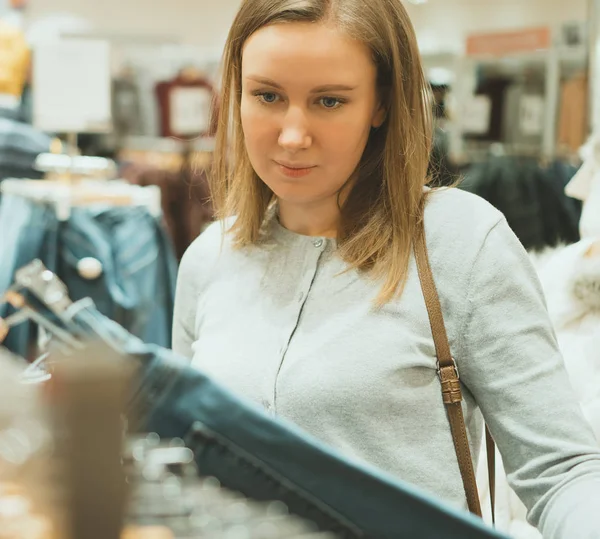 Vrouw kiezen jeans in kledingwinkel. — Stockfoto