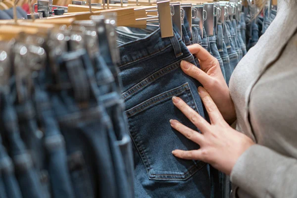 Woman choosing jeans in clothing store. — Stock Photo, Image