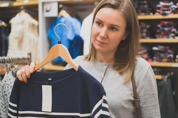 Жінка вибирає светр в магазині одягу . — стокове фото