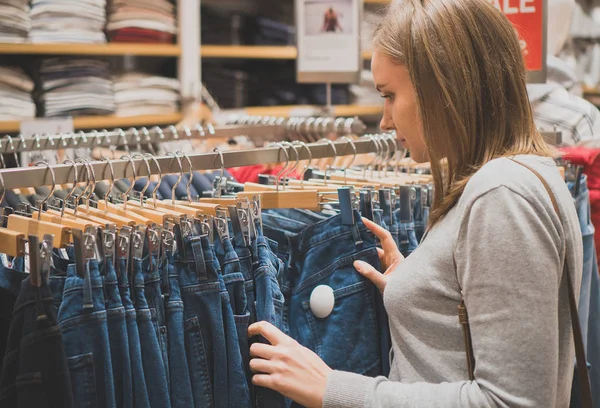 Vrouw kiezen jeans in kledingwinkel. — Stockfoto