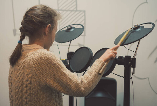 Little girl playing on electronic drums.