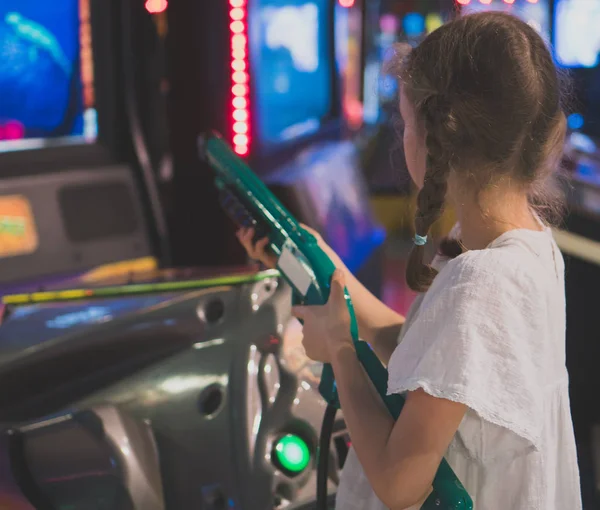 Liten flicka spela shooter spel i nöjesparken. — Stockfoto