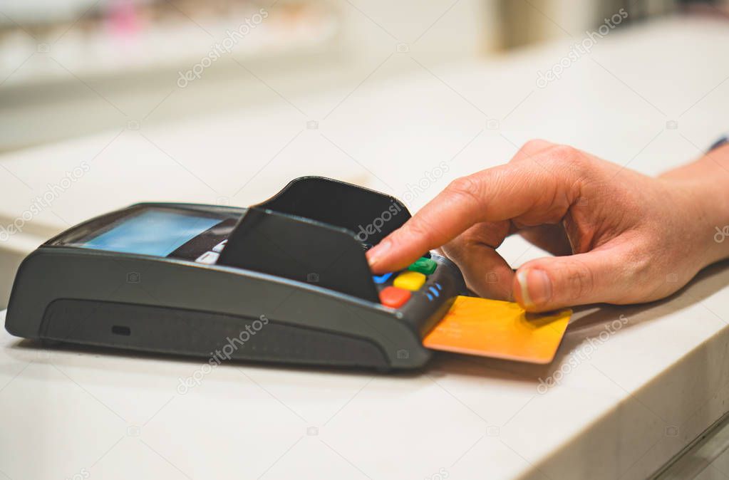 Woman makes payment via bank terminal in mall.