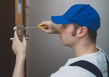 kapı kilidi değiştirme üniformalı genç tamirci.