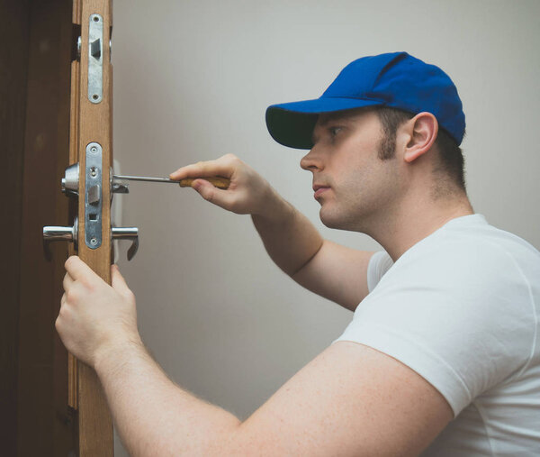 Молодой мастер в форме, переодевает замок.
.