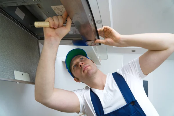Schöner Vorarbeiter repariert Abzugshaube in der Küche. — Stockfoto